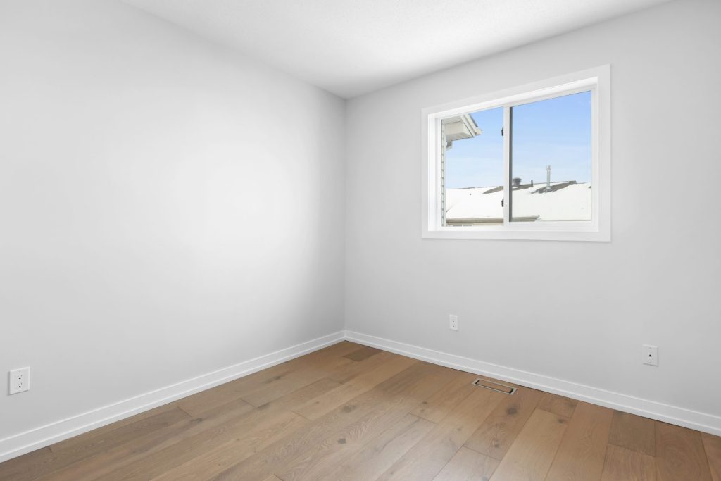 ein leerer Raum mit Fenster und Holzboden