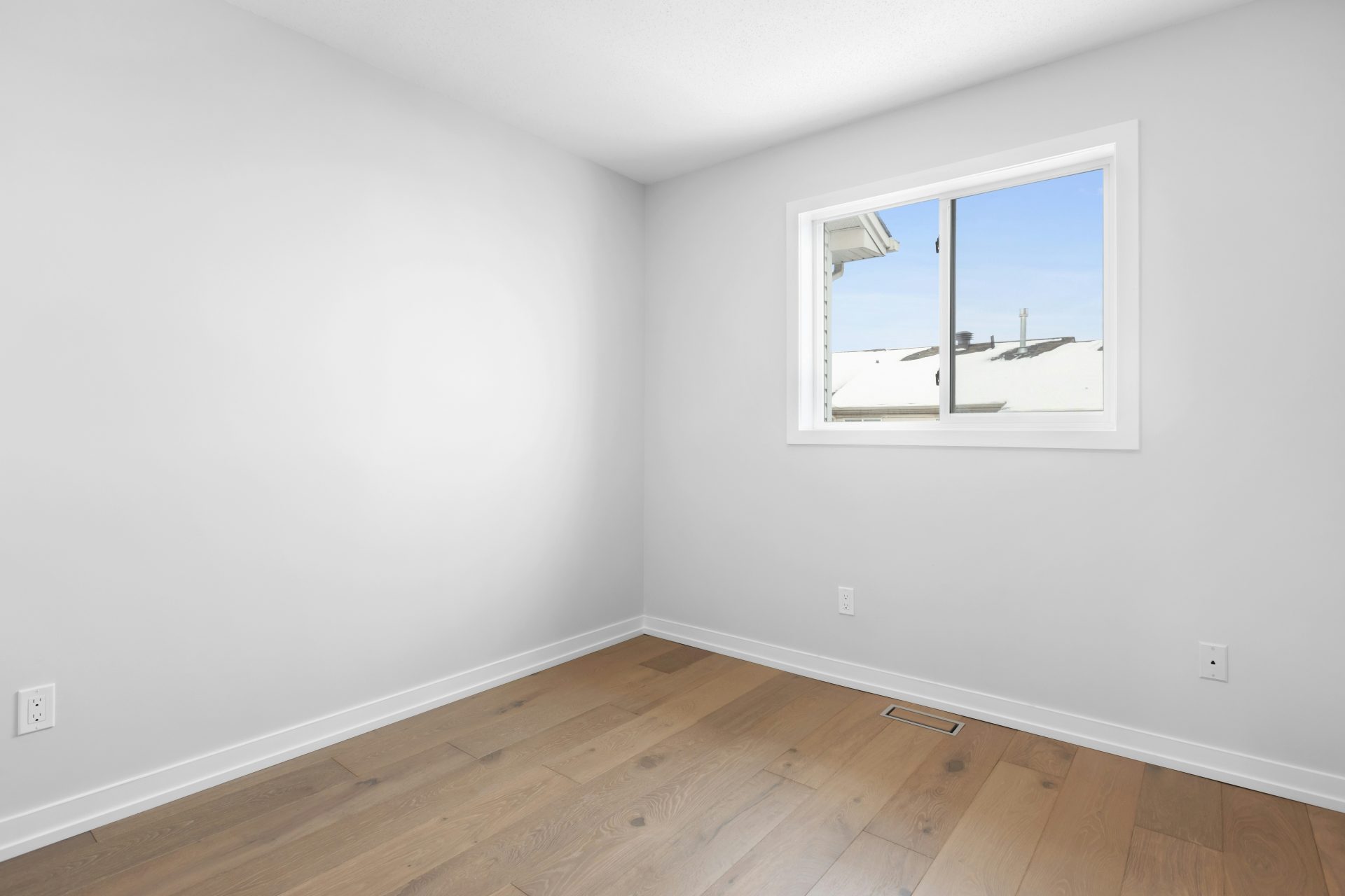 ein leerer Raum mit Fenster und Holzboden